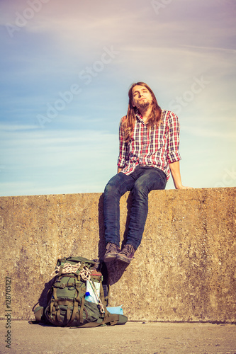 Man tourist backpacker sitting on grunge wall outdoor