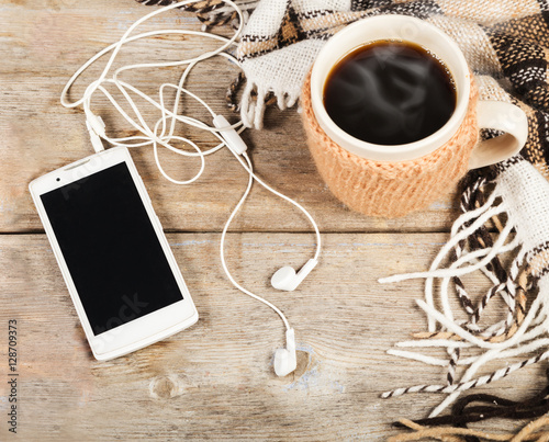 Hot coffee in a large cup, mobile phone with headphones