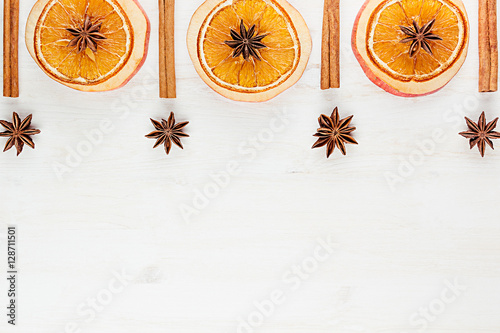 Christmas food - mulled wine background. Decorative frame of spice ingredients - anise stars, cinnamon, dried oranges and wine on wood white surface. Top view.