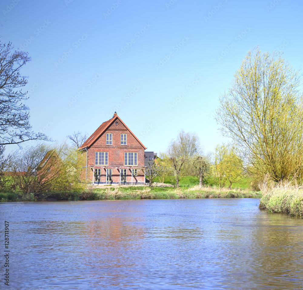 Idyllic river scene with old house and blue sky, spring scene. Idyllic river scene with old house and blue sky, spring scene.
