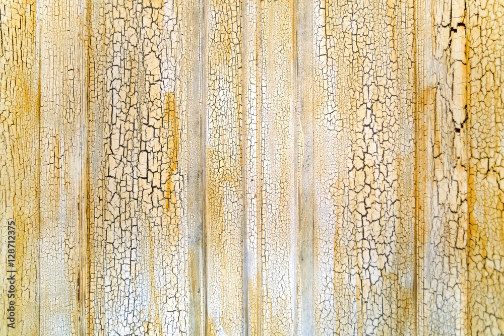 Naklejka premium Old wooden surface with cracked white paint and yellow spots, background, texture