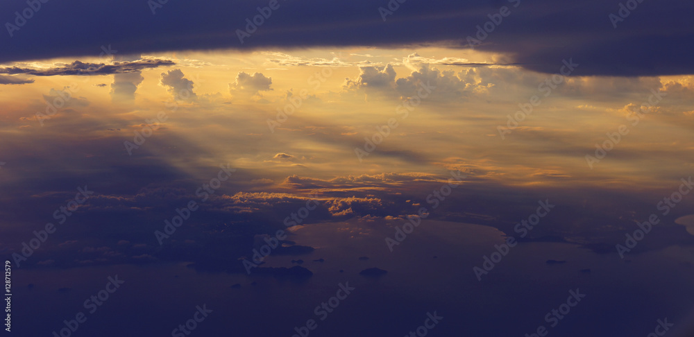 Fototapeta premium Light rays sunset shining through rich in space clouds,panorama