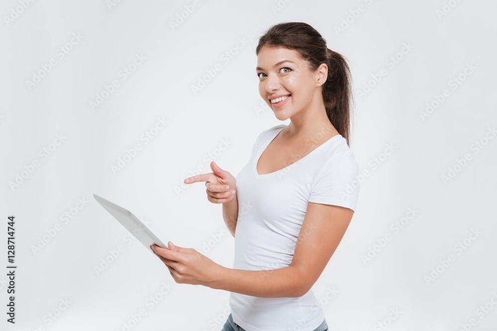 Cheerful woman holding digital tablet and pointing on it Cheerful woman holding digital tablet and pointing on it