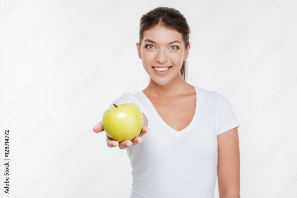 Cheerful woman holding apple and showing to camera. Cheerful woman holding apple and showing to camera.