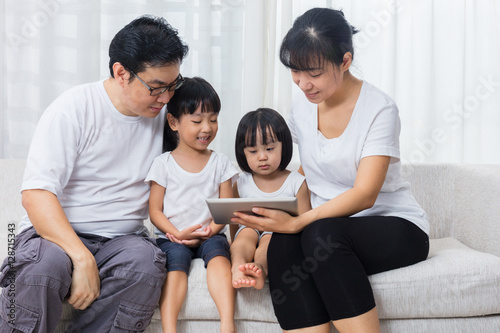 Asian Chinese parents and daughters using tablet on the sofa