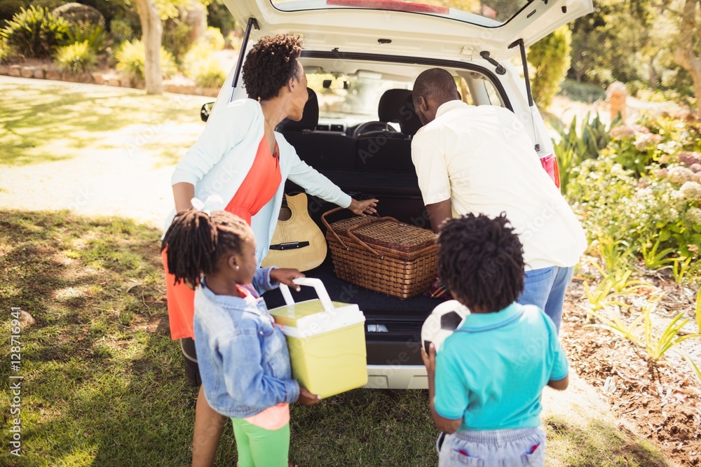 Happy family taking objects out of the car