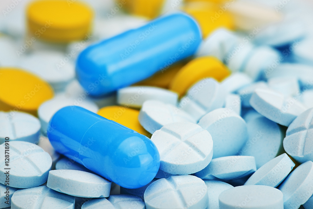 two light blue pills on a pile of medical pills two light blue pills on a pile of medical pills