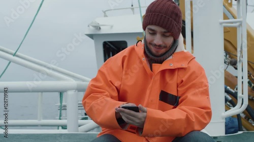 Casualy Dressed Fisherman Using Mobile Phone while Traveling on Ship. Shot on RED Cinema Camera in 4K (UHD). 