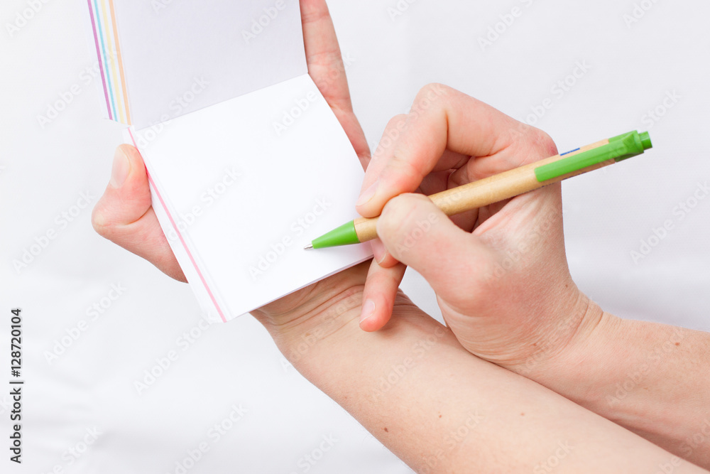 Hand holds notebook open. Blank white paper. Place for an inscription Hand holds notebook open. Blank white paper. Place for an inscription