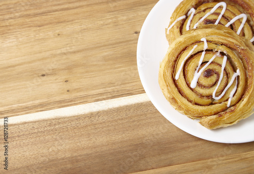 A plate of freshly baked cinnamon swirls on a wooden kitchen counter background with blank space at side
