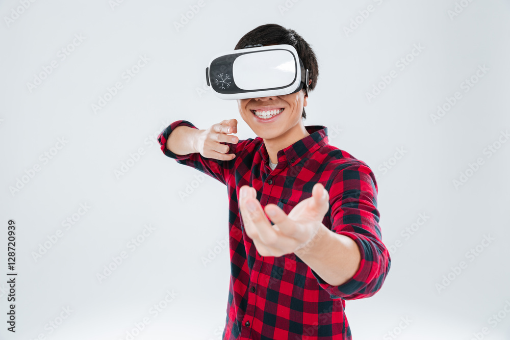 Fototapeta premium Happy man wearing virtual reality device and holding imagined gun