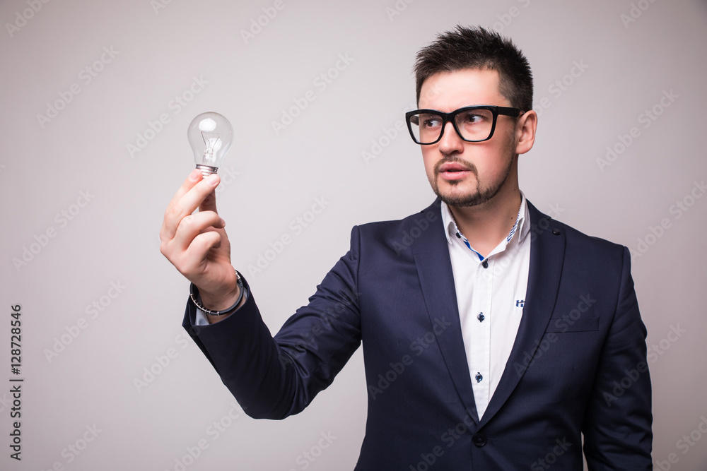 Handsome man in suit and glasses demonstrate light bulb Handsome man in suit and glasses demonstrate light bulb