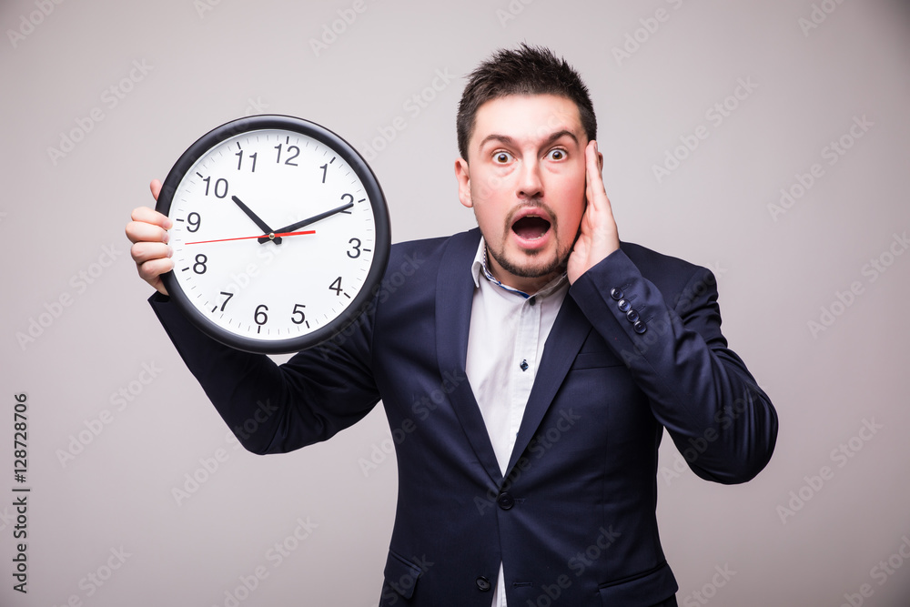 Worried bearded young man in suit with clock in hands miss something Worried bearded young man in suit with clock in hands miss something