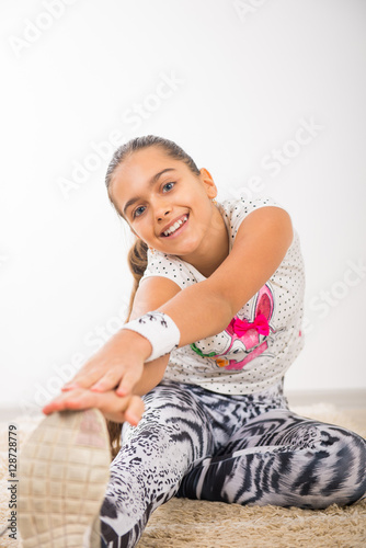 Beautiful teenage girl doing stretching exercises, girl on the carpet at home exercise. Beautiful teen girl Physical exercise doing in home environment, physical exercise for schoolchildren 
