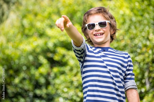 Portrait of cute boy with sunglasses pointing something