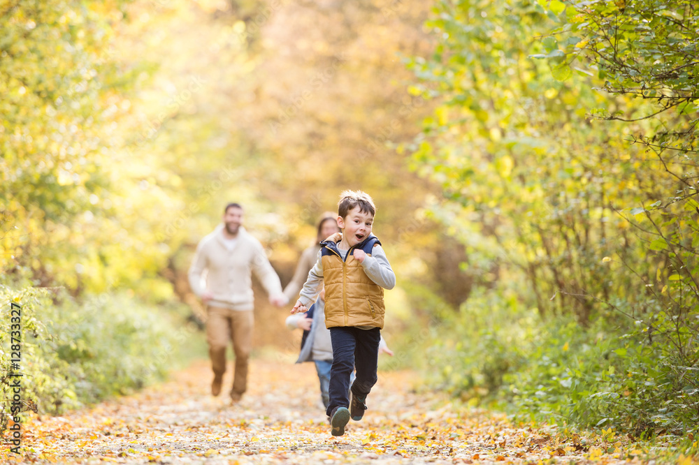 Beautiful young family on a walk in autumn forest.