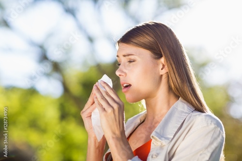 Beautiful woman using tissue while sneezing photo