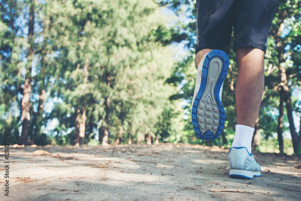Obraz premium close up foot of young runner man running along road in the park