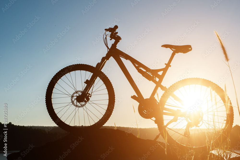 Fototapeta Silhouette Mountain biking on the rock at sky sunset