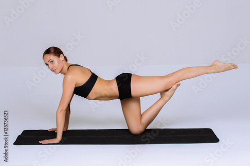  Fitness woman in sports skinny clothing looking away. Slim female model with flexible body. Horizontal studio shot with copy space on gray background.