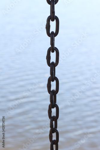 Metal chain links above water. © naiauss