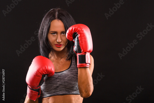 Boxing concept. Young fitness girl with boxing gloves looking at camera over black background.