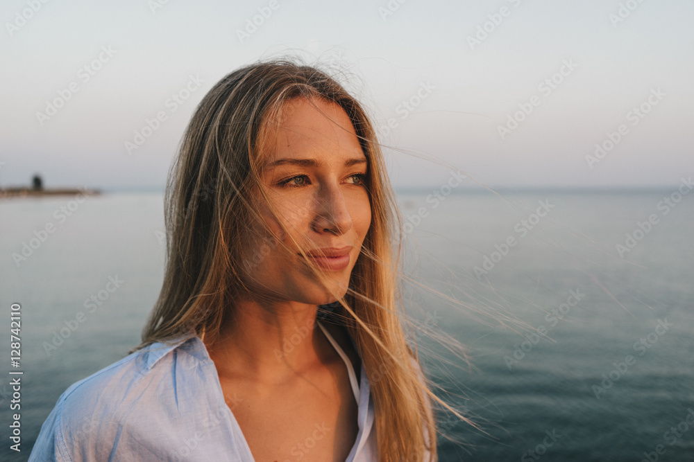 Portrait of young woman in front of the sea at sunset Portrait of young woman in front of the sea at sunset