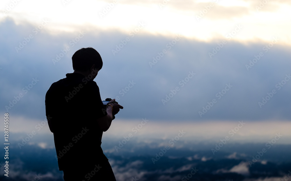 silhouette of the man. in his hand have a camera. he is taking a photo.