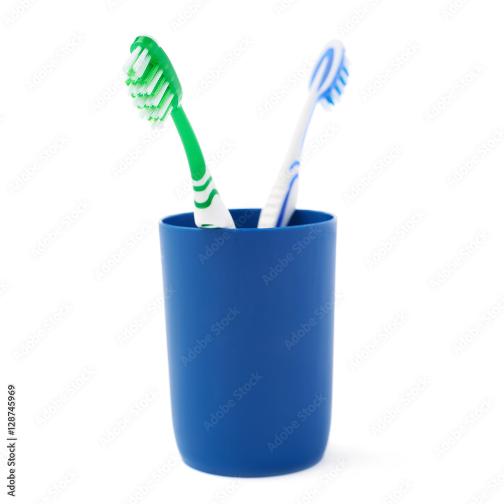 Pair of toothbrushes in blue plastic cup isolated over white background Pair of toothbrushes in blue plastic cup isolated over white background