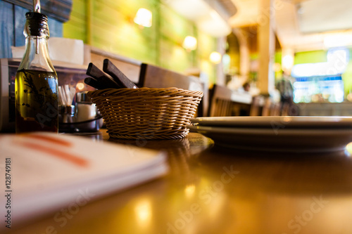 Restaurant menu and basket with cutlery on basket and plates on wooden table