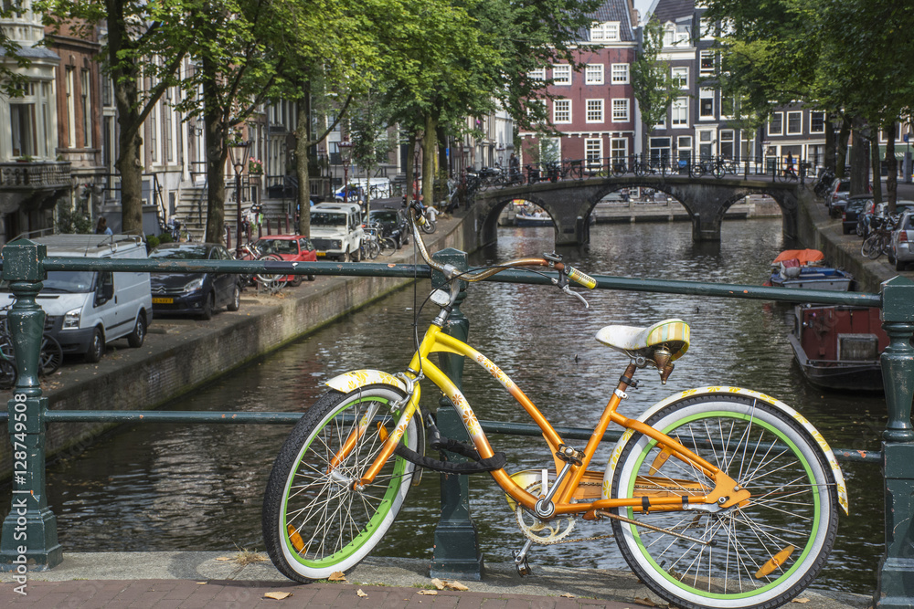 Yellow and green bike with old bridge and several buildings in Amsterdam