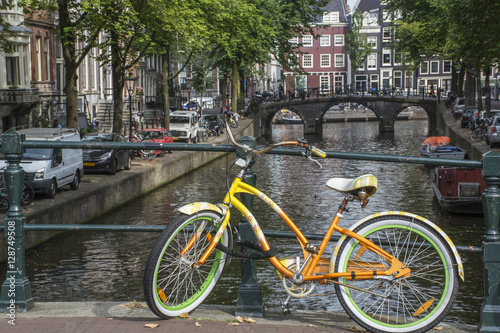 Yellow and green bike with old bridge and several buildings in Amsterdam © Anastasia Pestova