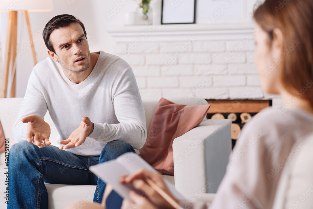 Fototapeta premium Emotional distressed man talking with psychologist