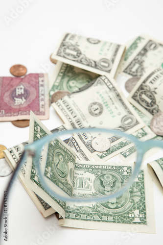 diverse currency through glasses, focused and blurry money on white backgrounds