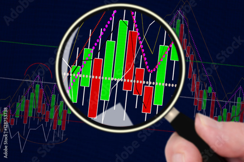 Hand with magnifying glass in front of chart