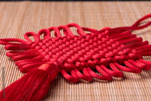 Chinese New Year decoration: Detail of red Chinese knot on bamboo mat, selective focus