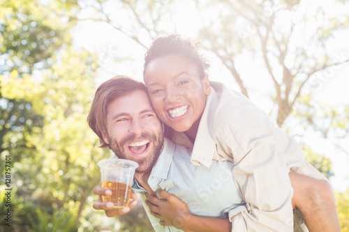Man giving piggyback to woman while having glass of beer Fototapet