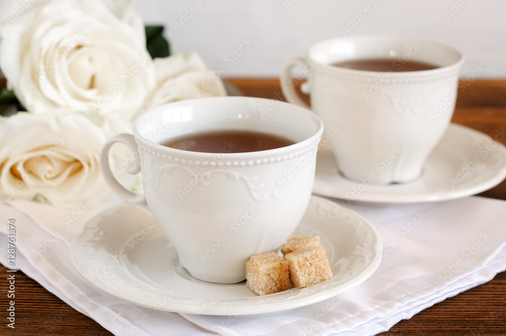 Tea in elegant porcelain cups and flowers