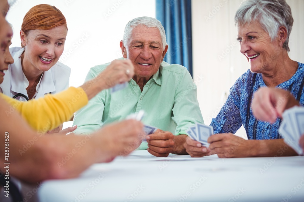 Smiling nurse and seniors people playing cards Smiling nurse and seniors people playing cards