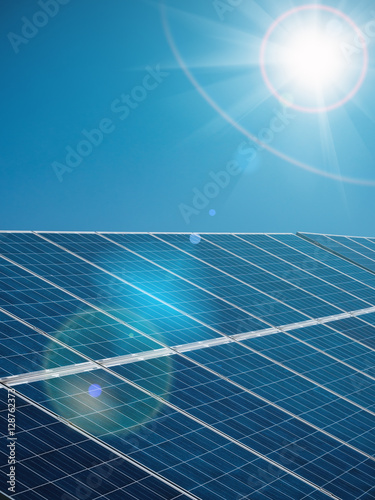 Futuristic sunny background of solar power plant with sun and blue sky