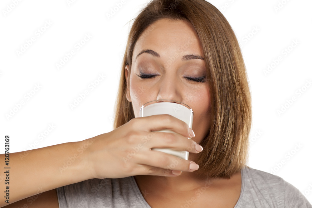 Young beautiful woman drinking milk from a glass