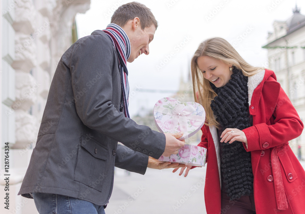 Handsome Young Man Giving His Girlfriend a Gift Box While Standing on the Street. Love and Valentines Day Concept.