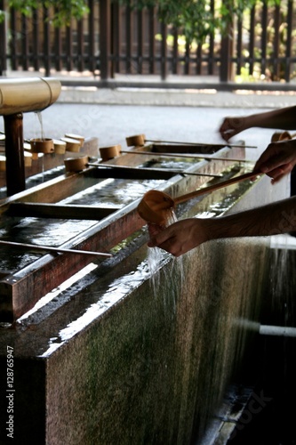 A man washing his hands with a traditional wooden ladle before entering the temple