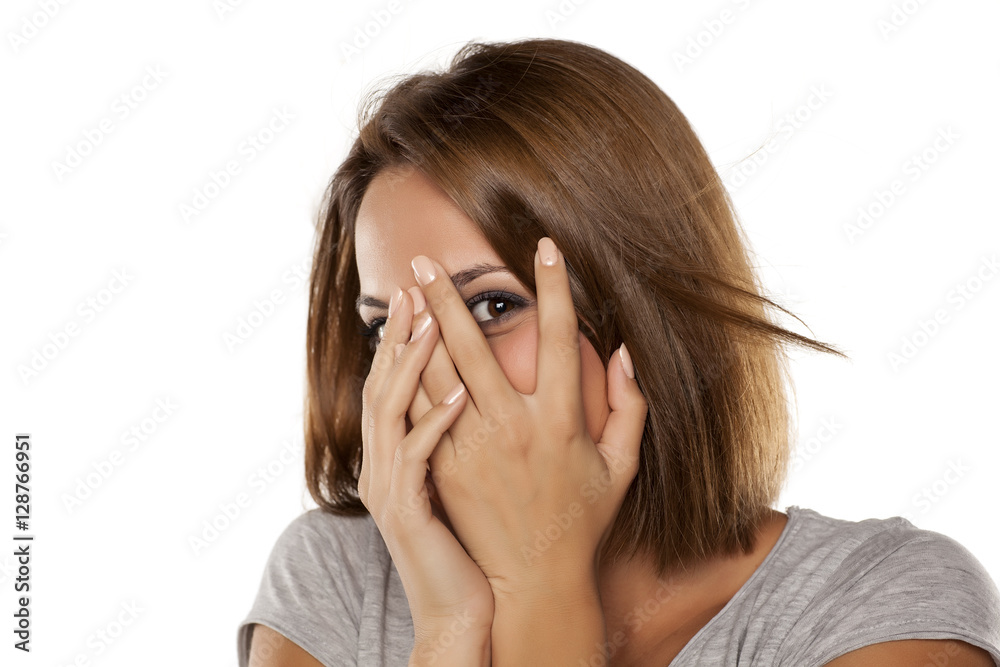 happy young woman covers her face with her hands and peep through her fingers happy young woman covers her face with her hands and peep through her fingers