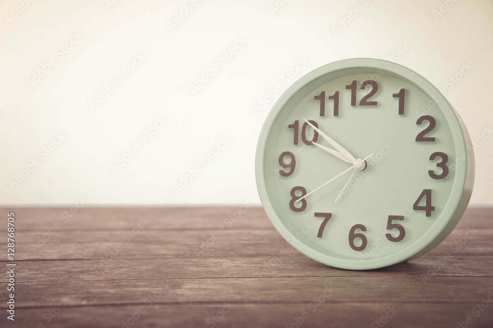 The clock on wooden table and white background vintage style The clock on wooden table and white background vintage style