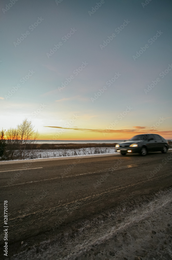 winter road at the snow-covered coast of the lake against the background of a bright decline. winter road at the snow-covered coast of the lake against the background of a bright decline.