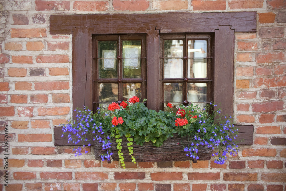 Window in an old brick wall With flowers on windowsill