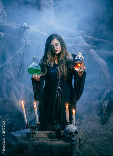 Foto Attractive witch is looking at the camera and holding in both hands the magic po