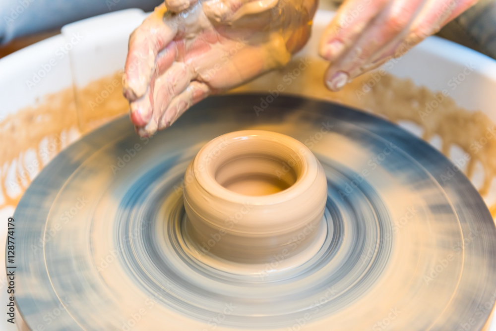 Fototapeta premium womens hands of a potter creating an earthen jar