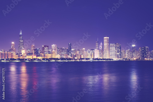 Vintage toned picture of Chicago city skyline with reflection in Lake Michigan at night  USA.